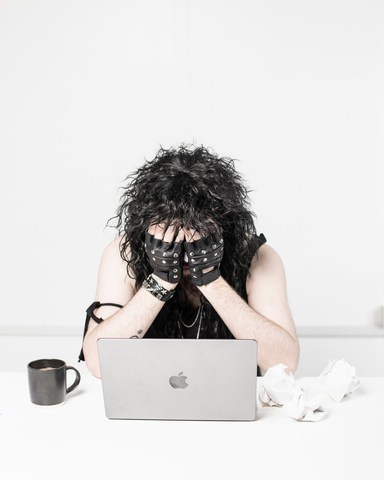 emotionally exhausted woman at workplace desk with head in hands