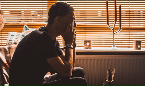 man frustrated with work stressed out and sitting with head on hands