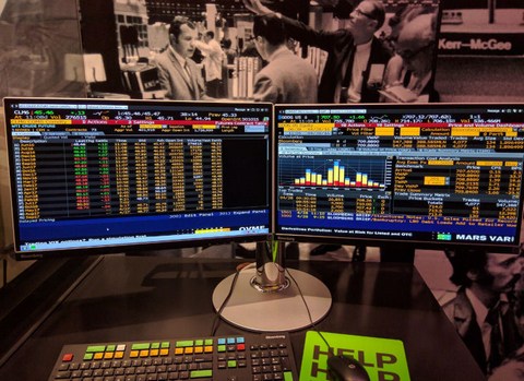 two financial computer monitors showing serious information