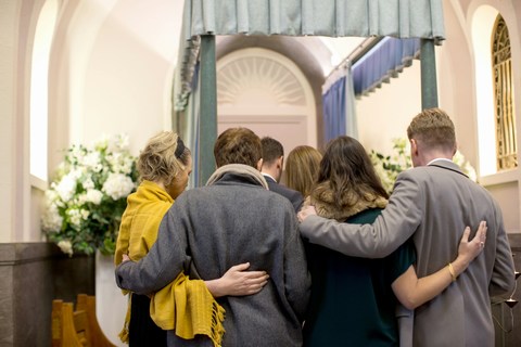 family at funeral standing near casket of parent