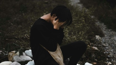 Grieving man with face in hands, sad.
